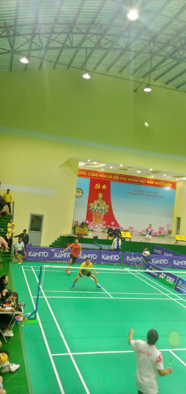 ''People playing badminton in a gym

Description automatically generated''